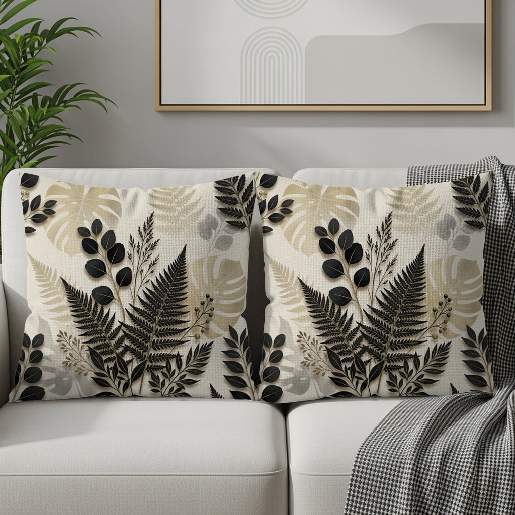 Two throw pillows with a black and beige fern leaf pattern on a sofa.