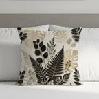 Cushion with black and beige botanical leaf pattern on a bed.