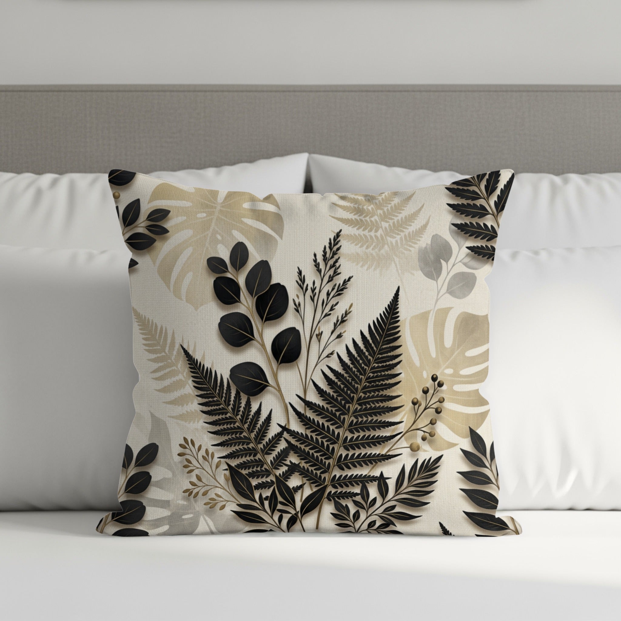Cushion with black and beige botanical leaf pattern on a bed.