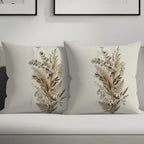 Two neutral throw pillows with dried floral and botanical print on sofa.
