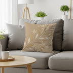Beige throw pillow with embossed floral vine pattern on a gray sofa.