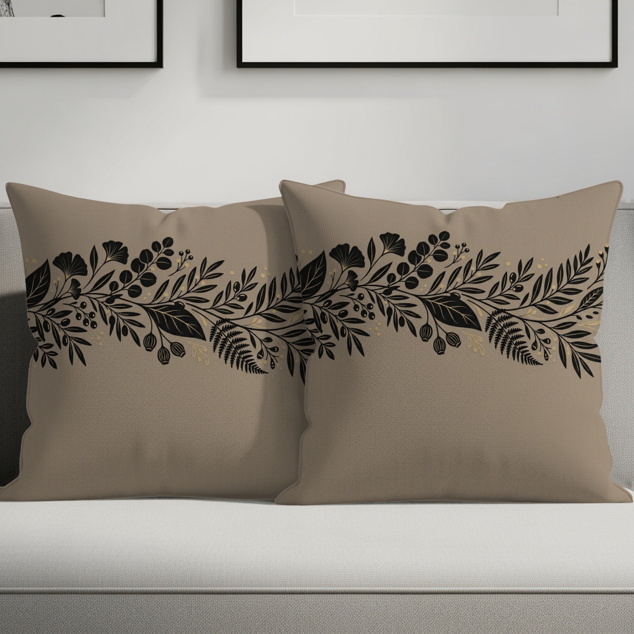 Two tan throw pillows with black floral and leaf border design.