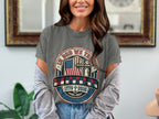 Gray t-shirt with "In God We Trust" seal, American flag, and cross.