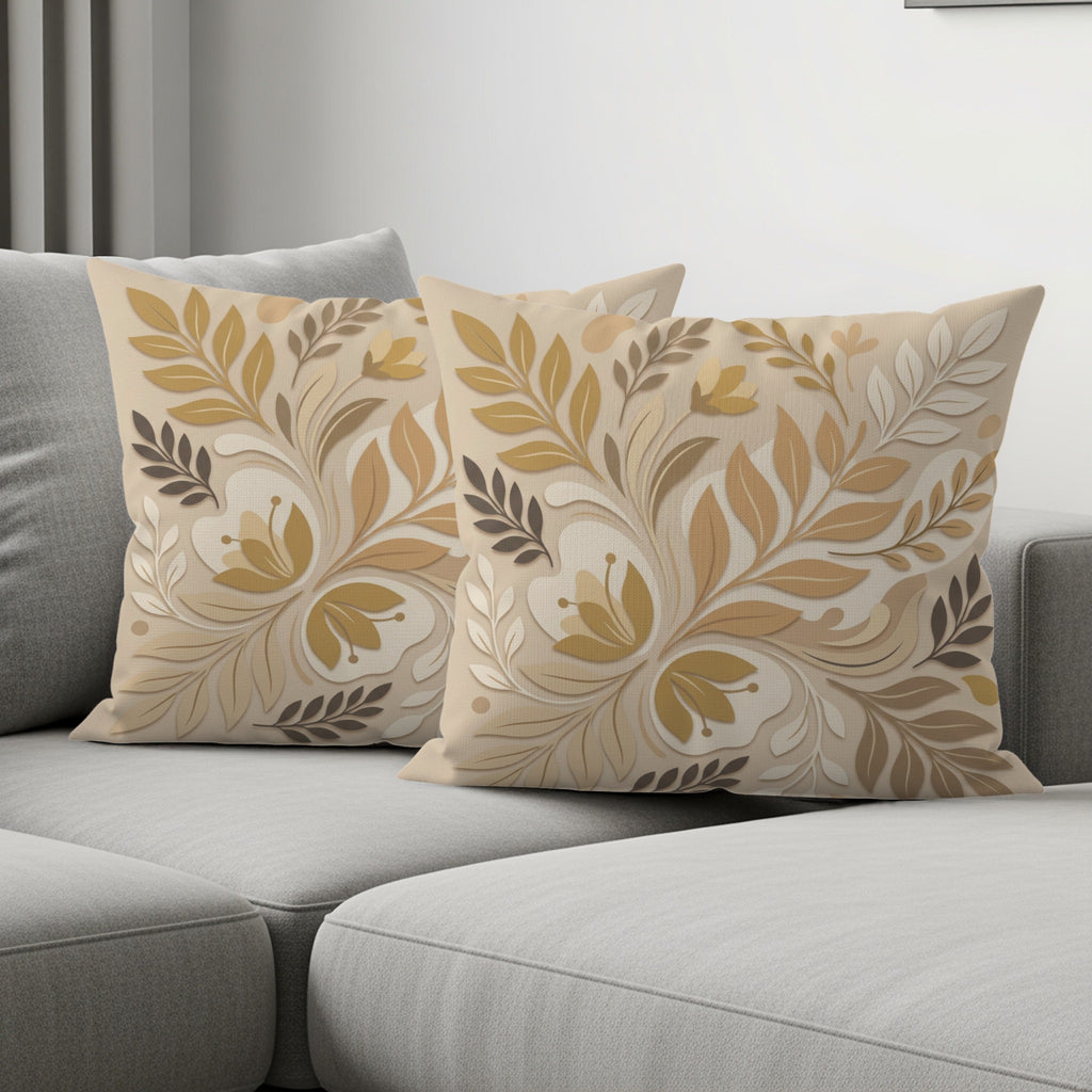 Two decorative throw pillows with a muted floral and leaf pattern on a gray sofa.