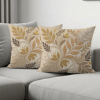 Two decorative throw pillows with a muted floral and leaf pattern on a gray sofa.