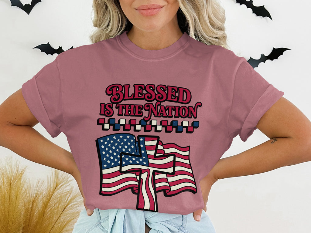 "Blessed is the nation" text with American flag graphic on dusty rose t-shirt.