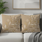 Two beige throw pillows with raised floral patterns rest on a white couch.