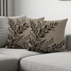 Two beige throw pillows with a dark floral pattern arranged on a sofa.