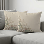 Two beige throw pillows with a delicate floral embroidery pattern.