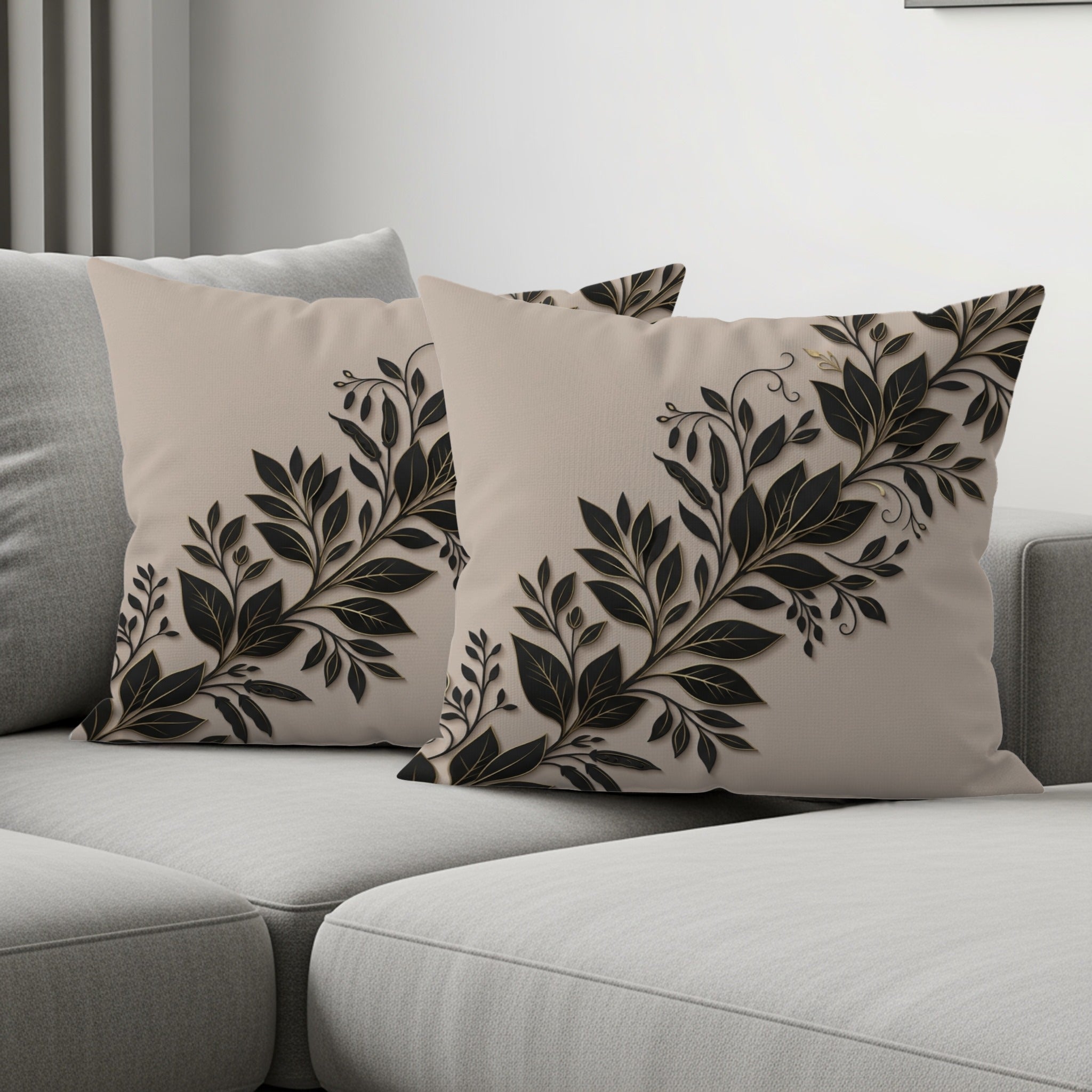 Two beige decorative pillows with black floral design on a sofa.
