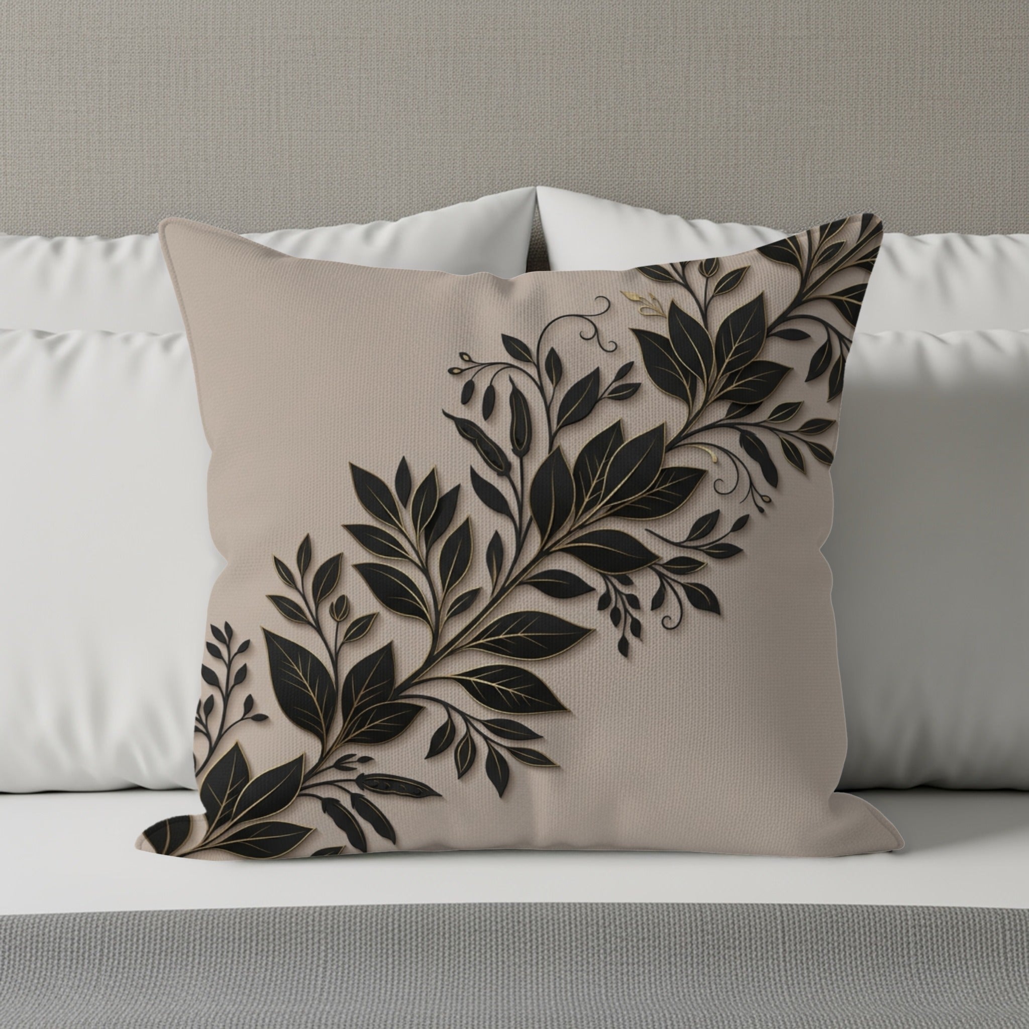 Beige pillow with raised black and gold leaf design on white pillows and bed.