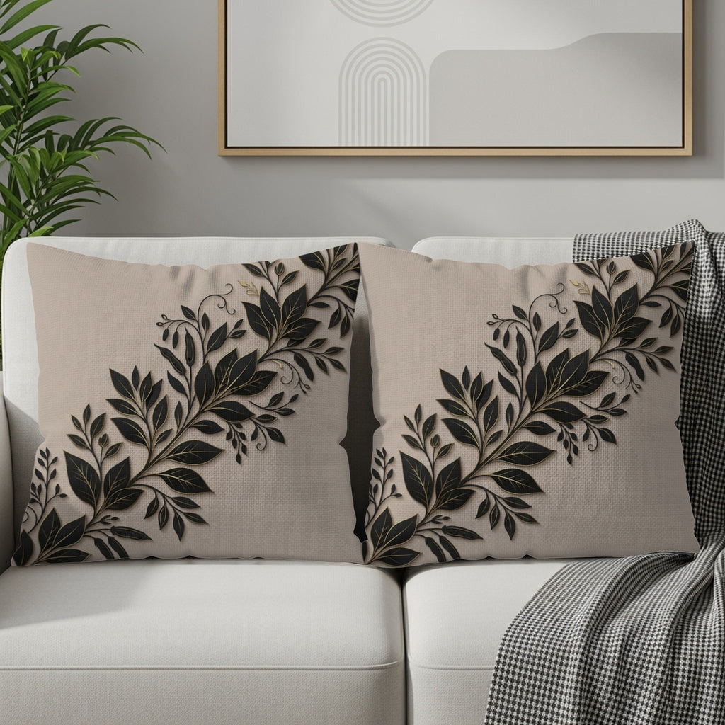 Two decorative throw pillows with a black leaf and vine pattern on a beige background.