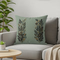 Sage green throw pillow with two symmetrical gold and dark green floral designs.