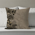 Tapestry cushion with black and gold tropical leaf pattern on a beige background.