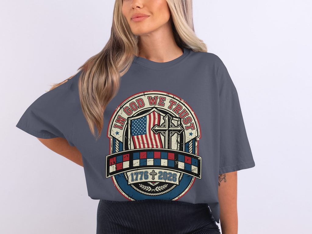 Gray t-shirt with patriotic graphic featuring American flag, cross, and "In God We Trust 1776 2023".