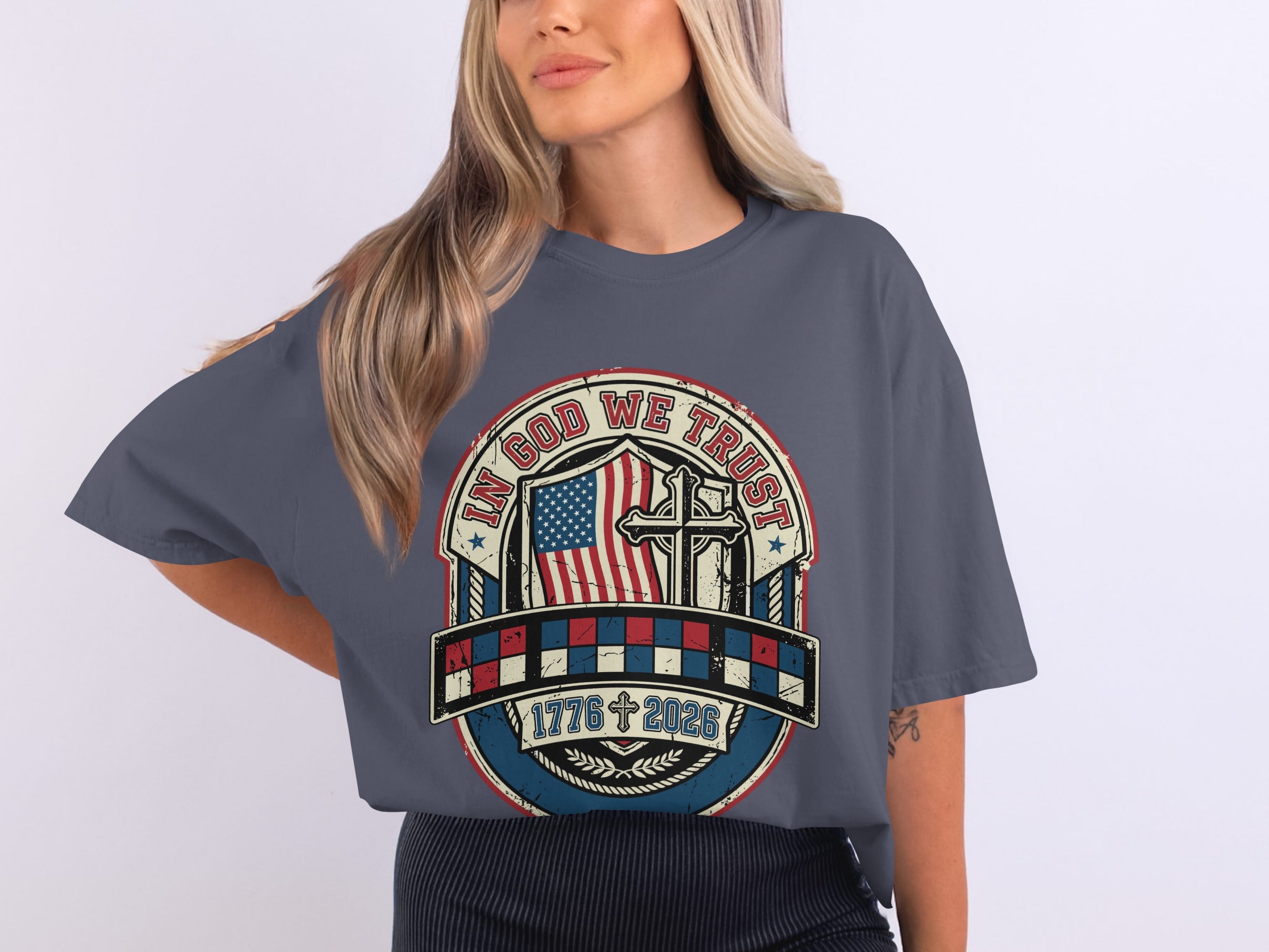 Gray t-shirt with patriotic graphic featuring American flag, cross, and "In God We Trust 1776 2023".