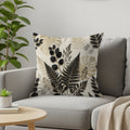 Throw pillow with a black and beige botanical leaf pattern on a sofa.
