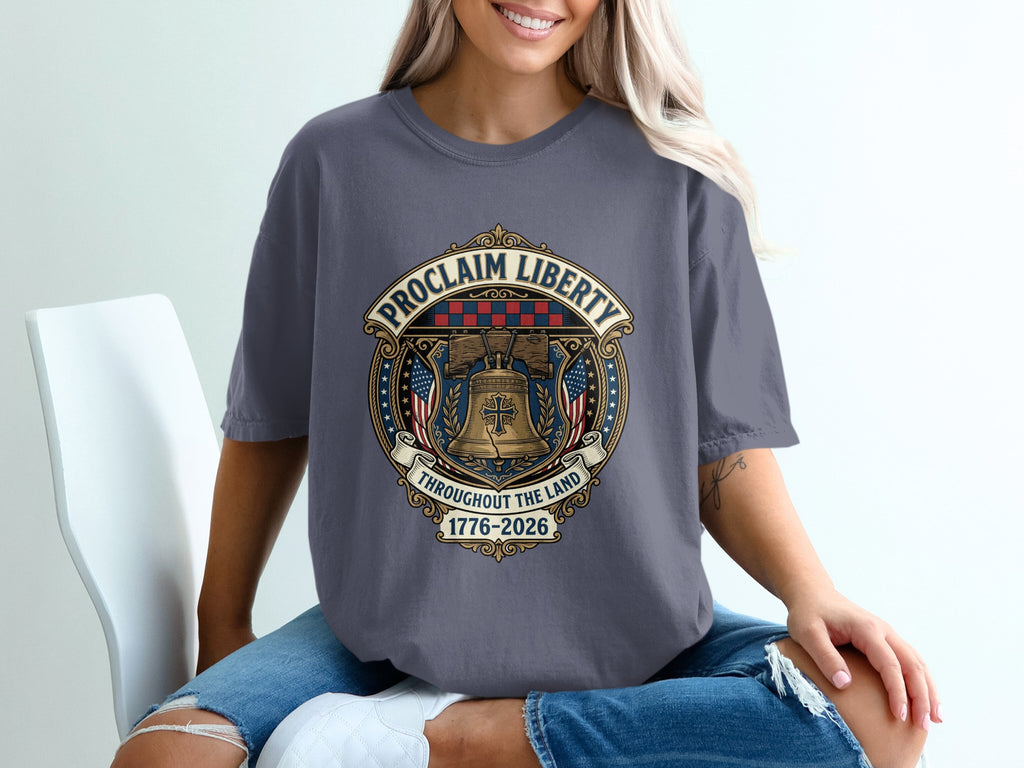 T-shirt with "Proclaim Liberty" emblem featuring the Liberty Bell, flags, and dates 1776-2026.