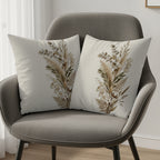 Two cream throw pillows with dried floral and botanical prints on a gray armchair.