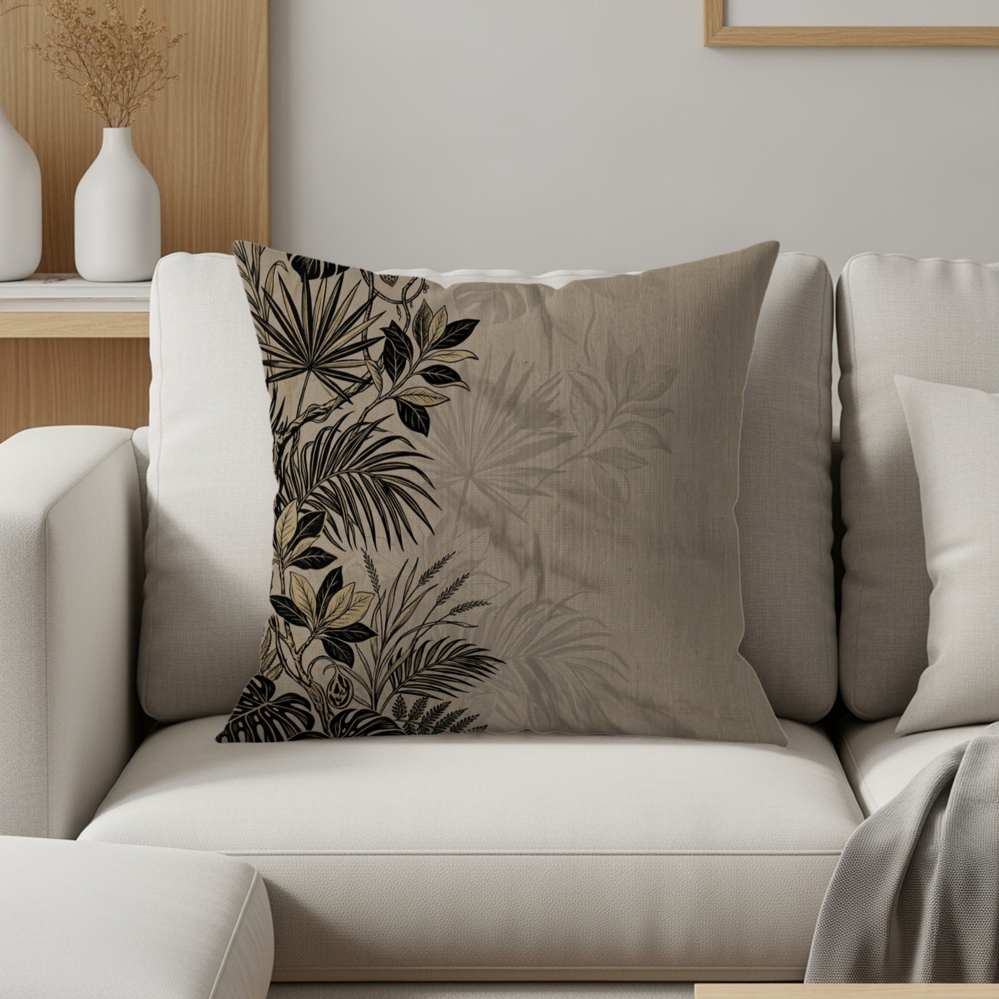 Tan throw pillow with a black and gold tropical leaf pattern.