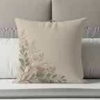 Beige pillow with subtle floral and leaf design in earthy tones.