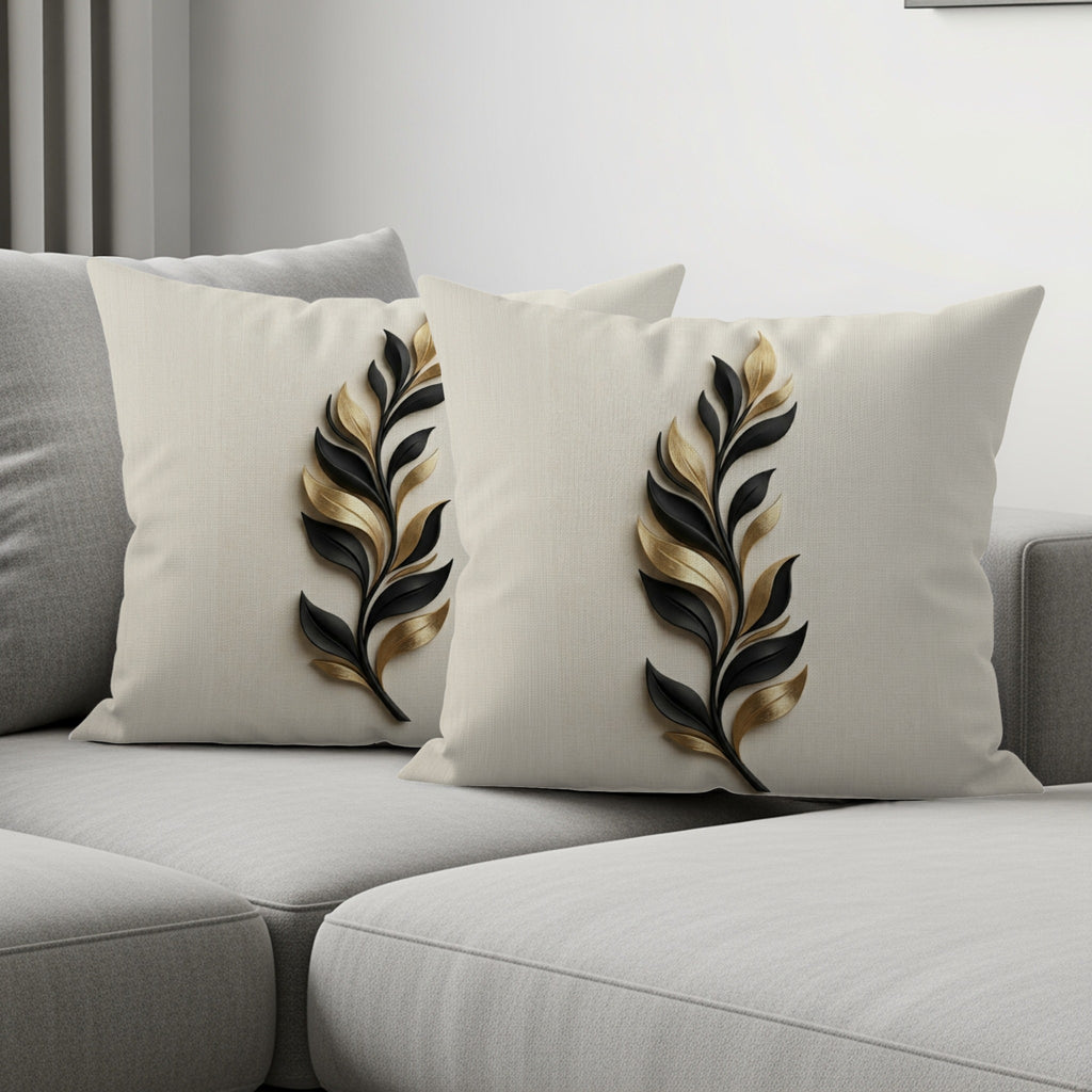 Two decorative throw pillows with gold and black leaf pattern on a sofa.