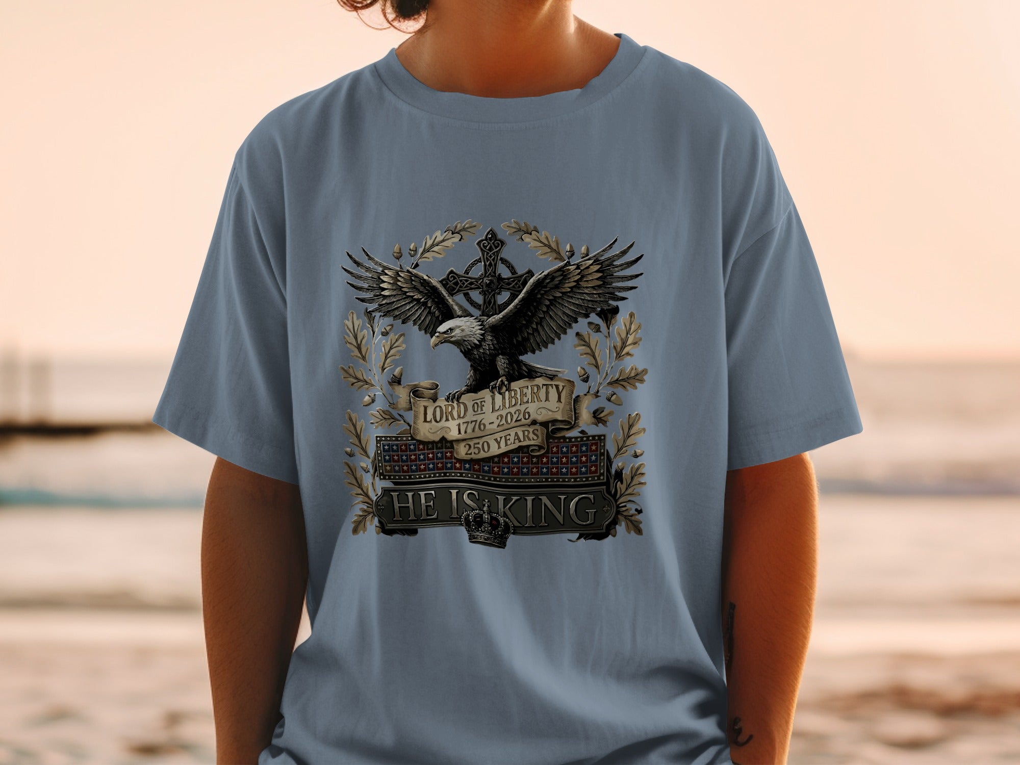 Blue t-shirt with an eagle, crown, and "Lord of Liberty 1776-2026 HE IS KING" text.