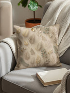 Beige throw pillow with delicate gold and green leaf pattern on armchair.