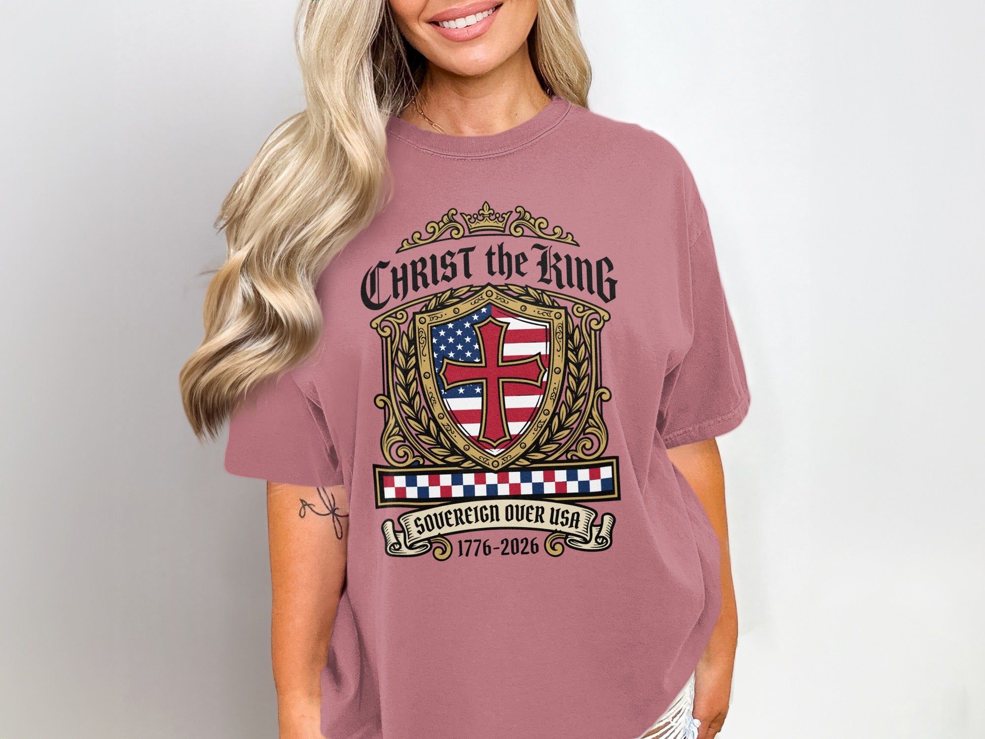 Pink t-shirt with Christ the King crest and "Sovereign over USA 1776-2026".