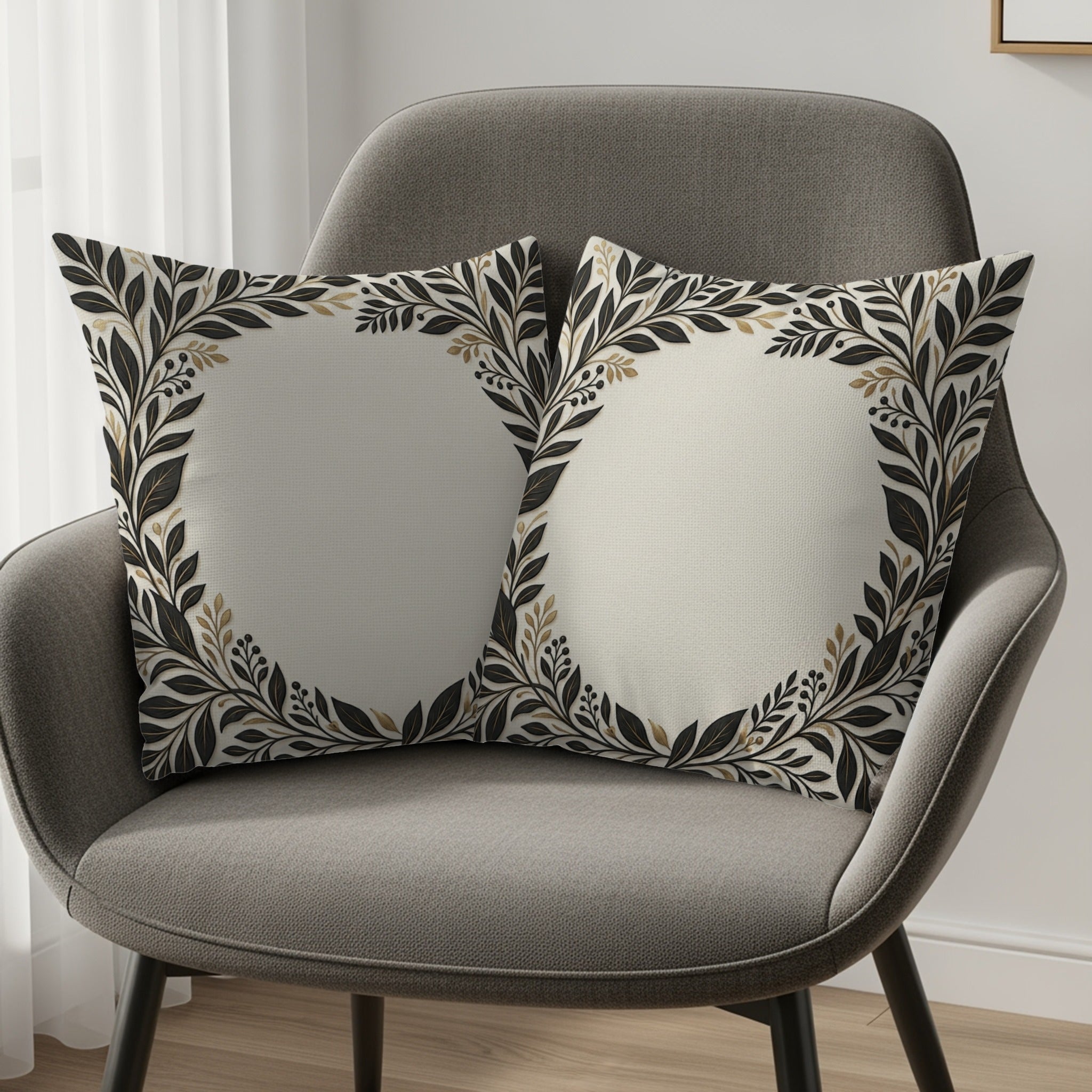 Two throw pillows with cream centers and black and gold floral borders on a gray chair.